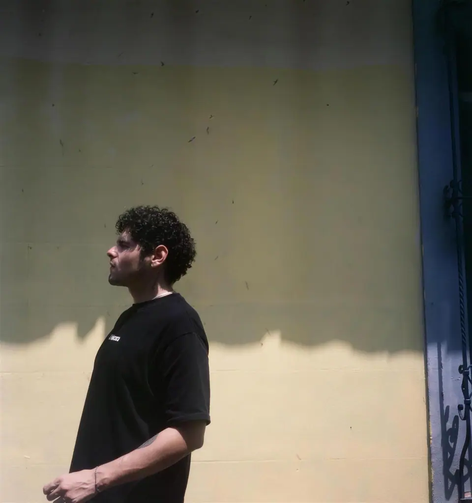 Juanito State in profile against a cream wall, Cali